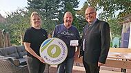 Die Öko-Modellregionmanagerin Laura Pircher und Gößweinsteins Bürgermeister Hanngörg Zimmermann (r.) übergeben die Förderplakette an Stefan Simmerlein.