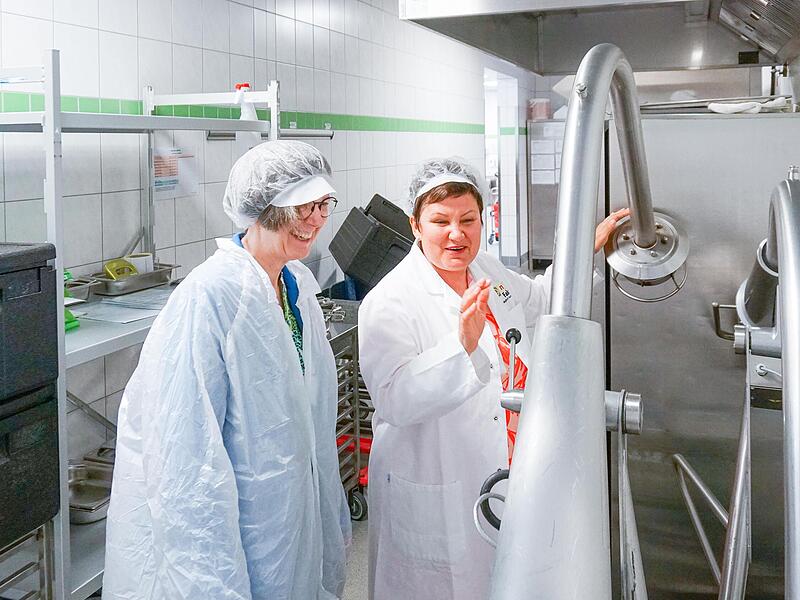 Marina Lofink, Betriebsleitung der Men&uuml;faktur Kulmbach, erl&auml;utert Sandra Schuhmann, Vorst&auml;ndin Soziales der Diakonie Bayern, die Abl&auml;ufe in der Produktion. Beeindruckt zeigte sich Schuhmann vom inklusiven Konzept der Men&uuml;faktur, die t&auml;glich rund 3...