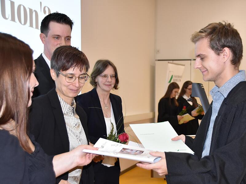 Marcel Bauer nimmt seine Bachelor-Urkunde von Dekanin  Janin Henkel-Oberländer (Mitte) entgegen.
