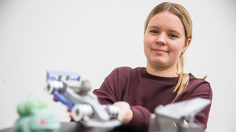 Feinmechanikerin Lena Pauer mit eigenen Werkstücken aus Metall und 3D-Druck.