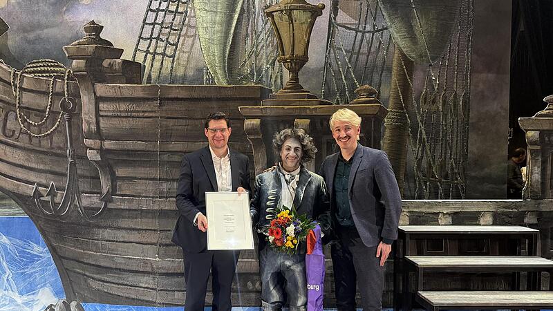 Oberb&uuml;rgermeister Dominik Sauerteig (links) und Intendant Neil Barry Moss &uuml;berreichen Michael Lion die Urkunde zu seiner Ernennung zum Kammers&auml;nger. Lion spielt in Wagners &bdquo;Fliegender Holl&auml;nder&ldquo; Sentas Vater Daland.
