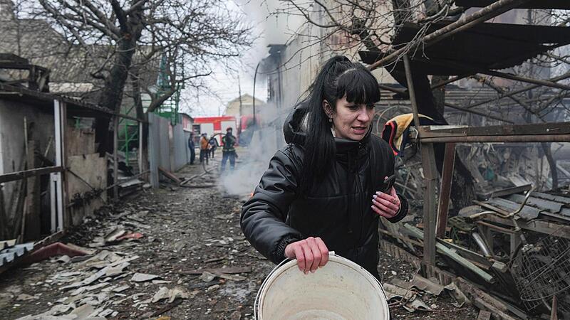 Ukraine, Mariupol: Eine Frau geht an den Trümmern nach russischem Beschuss vorbei. Russische Truppen haben ihren erwarteten Angriff auf die Ukraine gestartet.