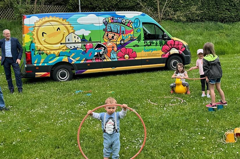 Kinder eröffnen am Spielplatz in Weihersbach die Saison des städtischen Spielmobils. Bürgermeister German Hacker (links) besucht sie.