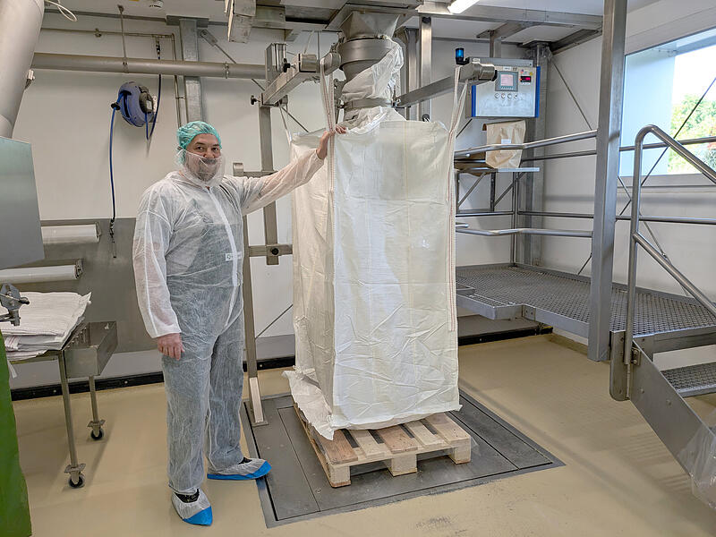 Benjamin Fochler, von Beruf Mischer und Lagerleiter, mit einem riesigen &bdquo;Teebeutel&ldquo;. Der Transportsack  fasst bis zu 700 Kilogramm frisch gemischte Teemischungen zur Auslieferung an Industriekunden oder zum Transport zur n&auml;chsten Verarbeitungsstufe.