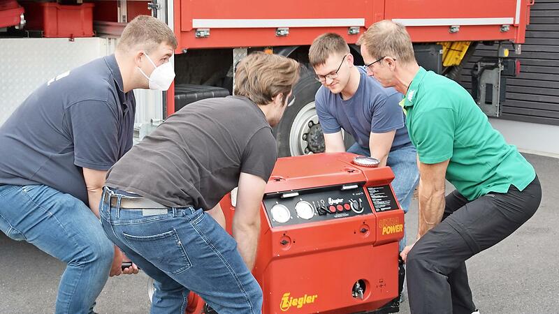Frank Schnabel (rechts) zeigt den Lehrgangsteilnehmern die richtige Standposition beim Heben einer Feuerwehrpumpe von ann&auml;hernd 150 Kilogramm Gewicht.