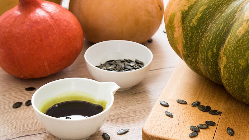 K&uuml;rbiskern&ouml;l ist neben K&uuml;rbissen zu sehen