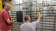 Jürgen Obermeier (links) und Matthias Engert stecken die Teile auf ein Gestell, auf dem die Metallstücke dann pulverbeschichtet und gebrannt werden.