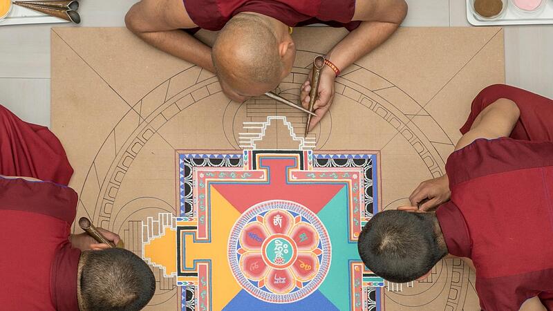 M&ouml;nche gestalten ein Sandmandala.