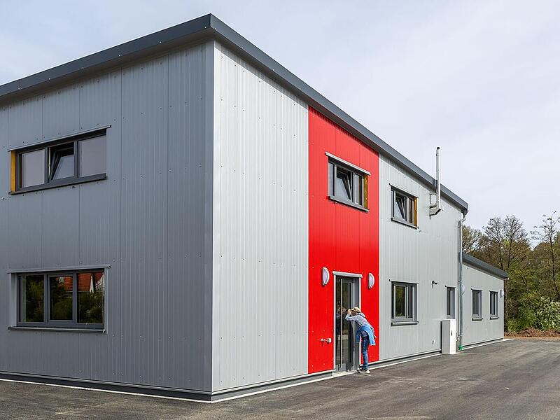 Ein Feuerwehrgeb&auml;ude, das alle Normen erf&uuml;llt. Rechts die Stellpl&auml;tze f&uuml;r die Privat-Pkws der Feuerwehrleute, links im Geb&auml;ude die Halle f&uuml;r die Einsatzfahrzeuge, rechts oben Lagerraum, darunter die notwendigen Funktionsr&auml;ume.