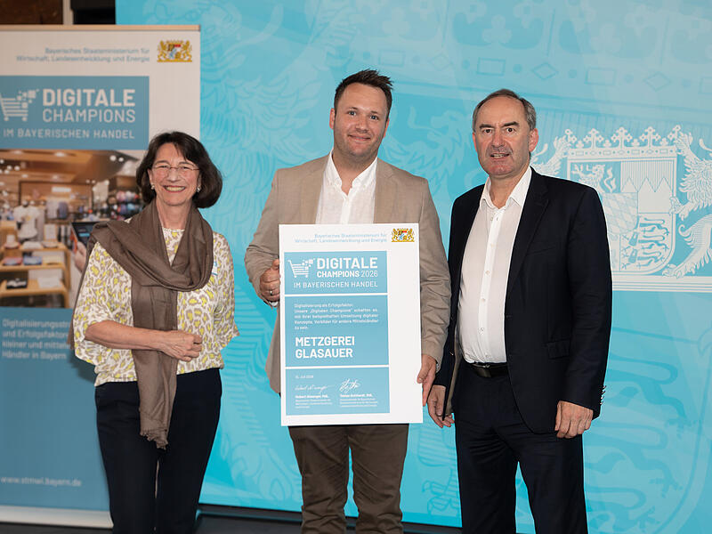 Bayerns Wirtschaftsminister Huber Aiwanger (r.) übergibt Dominik Glasauer die Urkunde „Digitale Champions im bayerischen Handel 2026“, links daneben Michaela Pichlbauer von der Rid-Stiftung. Bayerns Wirtschaftsminister Huber Aiwanger (r.) übergibt Dominik Glasauer die Urkunde „Digitale Champions im bayerischen Handel 2026“, links daneben Michaela Pichlbauer von der Rid-Stiftung.