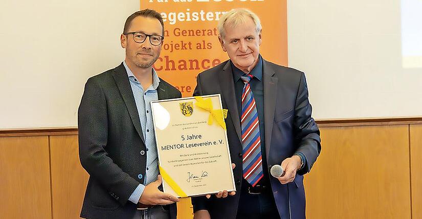 Stellvertretender Landrat Bruno Kellner (r.) überreicht Christian Lorenz, Leiter des Bildungsbüros und Vorstandsmitglied des Mentor-Vereins, die Urkunde zum fünfjährigen Jubiläum.