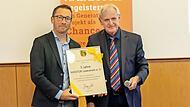 Stellvertretender Landrat Bruno Kellner (r.) überreicht Christian Lorenz, Leiter des Bildungsbüros und Vorstandsmitglied des Mentor-Vereins, die Urkunde zum fünfjährigen Jubiläum.