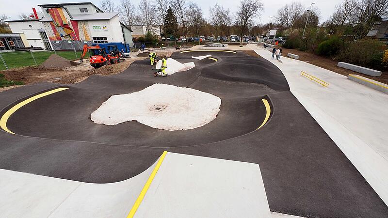 Die neue Trendsportanlage Skaterpark (links) und Pumptrack der neuen Trendsportanlage gegenüber des Hallenfreibades sind nahezu fertiggestellt. Bis zur Eröffnung am 11. Mai kommen noch Boulderwand, Parcourelemente und ein Basketballfeld hinzu. In den Mulden des Pumptracks ist noch das weiße Pflanzvlies zu sehen. Diese Stellen enthalten Grassamen und werden mit einer Schicht Mutterboden abgedeckt. Das Vlies verhindert, dass die Samen an den steilen Flächen ausgewaschen werden.
