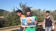 Mit einem Foto von Bundeskanzlerin Merkel gehen syrische Flüchtlinge in der Nähe von Budapest eine Straße in Richtung österreichische Grenze entlang. Am 4. September 2015 machten sich Hunderte Flüchtlinge in Ungarn auf Richtung Deutschland.