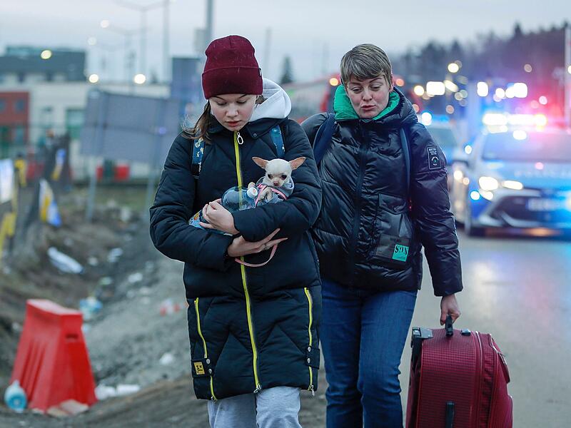 Ein Mädchen aus der Ukraine hält einen Hund, als sie mit einer anderen Frau am polnischen Grenzübergang Medyka ankommt.