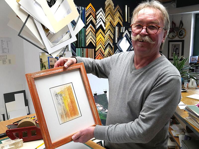 Back h&auml;lt den fertige Rahmen mit einem Bild von Michael Heide.