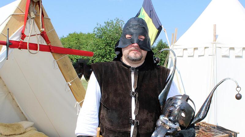 Mit einer Schandmaske im Arm steht &ldquo;Meister Johannes&ldquo; vor dem Zelt, in dem er w&auml;hrend der Mittelalterspektakel &uuml;bernachtet.