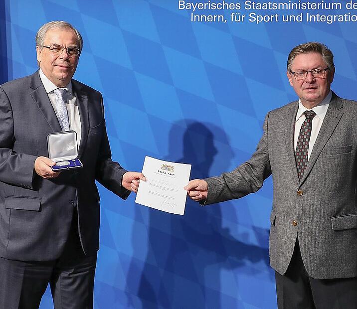 Gerhard Eck (rechts) übergibt Bernhard Ruß die Verdienstmedaille und eine Urkunde.