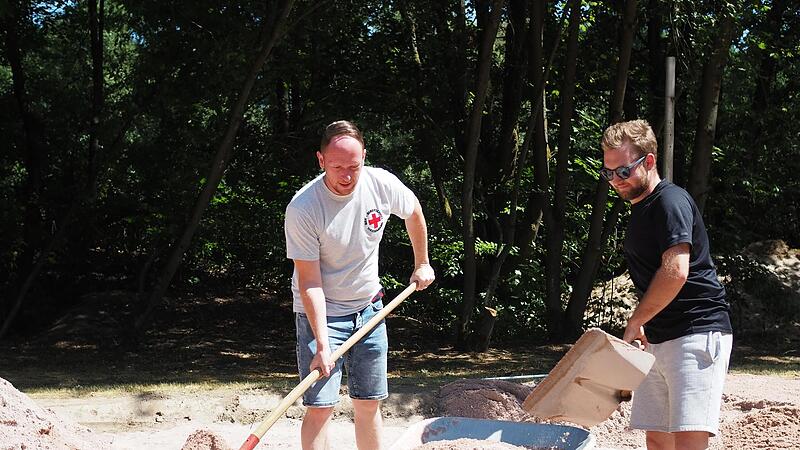 Timo Limmer und Luca K&ouml;hler verteilen den neuen Sand auf dem Beachvolleyballplatz. &nbsp;