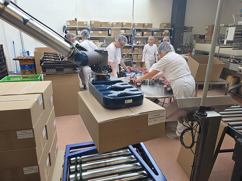 Ein Roboter nimmt den Mitarbeitern die schwere Arbeit ab, die Pakete auf die Paletten zu stellen.