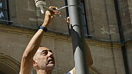 Louay Yassin montiert einen Sensor an einem Leuchtenmast.