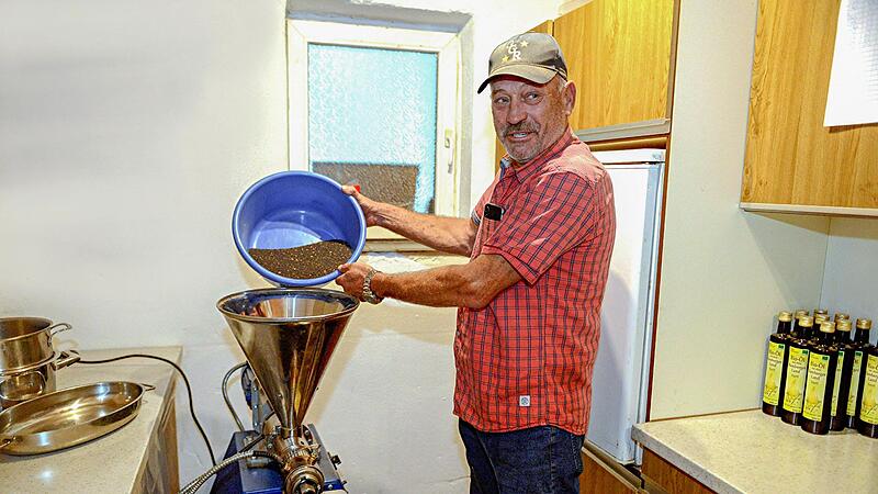 Harald Bogensperger schüttet Winterraps in den Trichter seiner Ölmühle,  die er in seiner Landwirtschaft in Burgebrach betreibt.