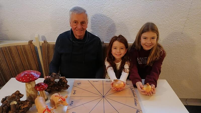 Lina und Marie (von rechts) pr&auml;sentieren die Zwiebeln, sp&auml;ter geben sie das Salz in die Schalen &ndash; dann muss eine Nacht dr&uuml;ber geschlafen werden. Opa Kurt sch&auml;tzt die Aussagen der Zwiebel.