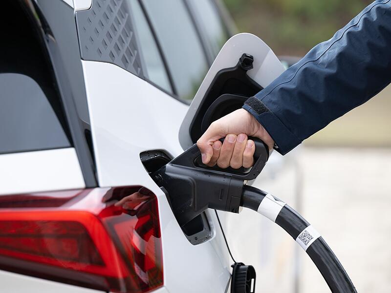 Ein Mann steckt ein Ladekabel in ein Elektroauto Ein Mann steckt ein Ladekabel in ein Elektroauto