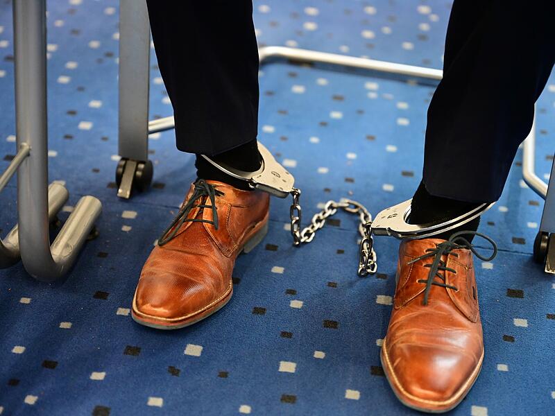 Der Angeklagte sitzt mit gefesselten Füßen im Gerichtssaal - damit er nicht flüchten kann