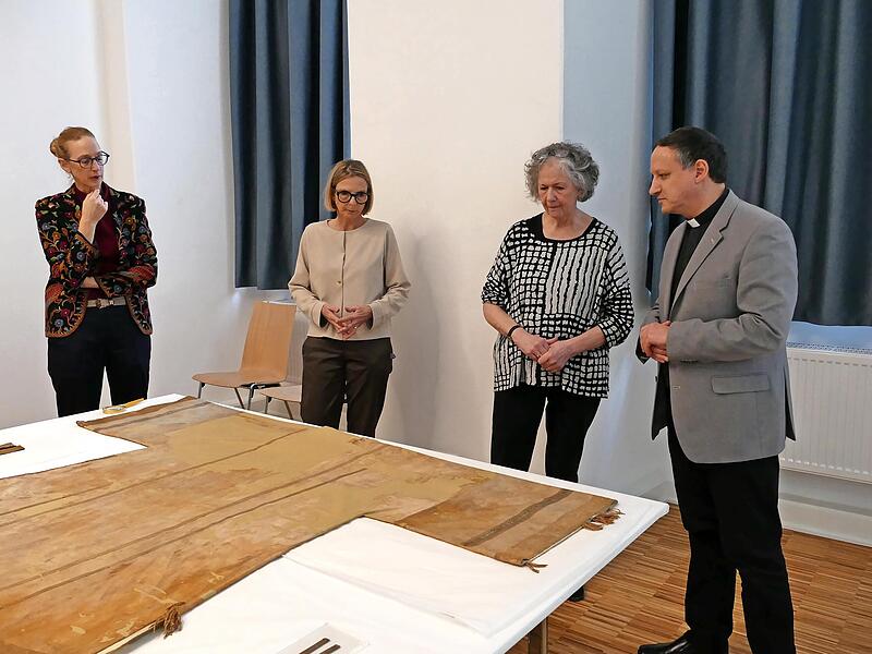 In der Pressekonferenz zeigten Museumschefin Carola Marie Schmidt (links) und Textilrestauratorin Sibylle Ruß (rechts) auch die 800 Jahre alte Dalmatik von Bischof Otto II., in der eine Fehlstelle auf den Textilfund verweist. In der Pressekonferenz zeigten Museumschefin Carola Marie Schmidt (links) und Textilrestauratorin Sibylle Ruß (rechts) auch die 800 Jahre alte Dalmatik von Bischof Otto II., in der eine Fehlstelle auf den Textilfund verweist.