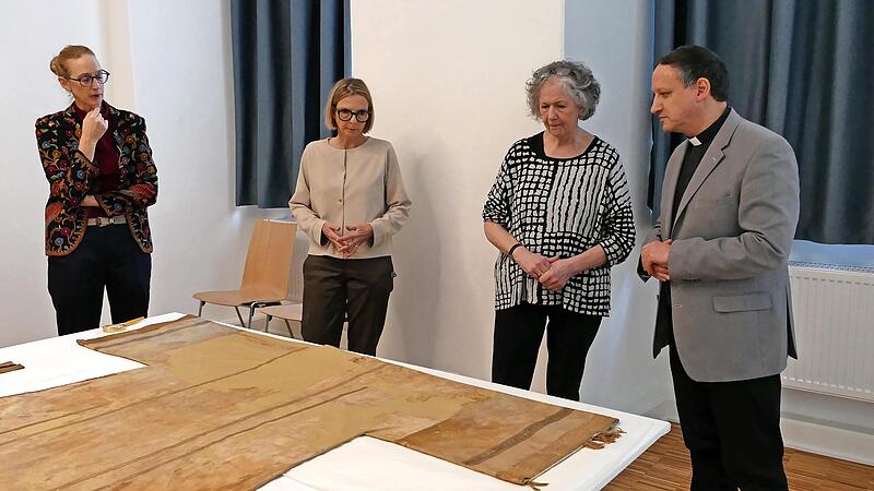 In der Pressekonferenz zeigten Museumschefin Carola Marie Schmidt (links) und Textilrestauratorin Sibylle Ruß (rechts) auch die 800 Jahre alte Dalmatik von Bischof Otto II., in der eine Fehlstelle auf den Textilfund verweist. In der Pressekonferenz zeigten Museumschefin Carola Marie Schmidt (links) und Textilrestauratorin Sibylle Ruß (rechts) auch die 800 Jahre alte Dalmatik von Bischof Otto II., in der eine Fehlstelle auf den Textilfund verweist.