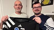 Matthias Oehrl, Sportlicher Leiter der TSSV F&uuml;rth am Berg (links) und Matthias Friedrich, sein Amtskollege beim TBVfL Neustadt/Wildenheid halten das erste frischbedruckte Trikot der geplanten Spielgemeinschaft in H&auml;nden. Die Fu&szlig;baller aus F&uuml;rth am Berg und Wildenheid wollen ab der Saison 2026/2027 mit insgesamt drei Mannschaften gemeinsam auf Torejagd gehen.