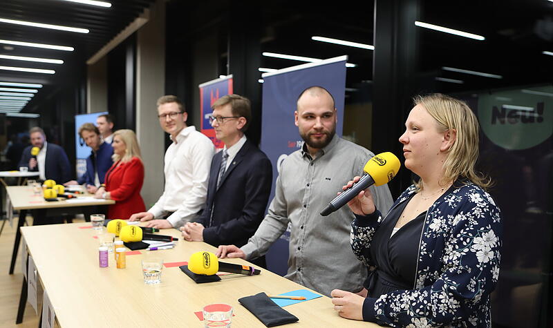 Claudia John (Freie W&auml;hler, von rechts) im Gespr&auml;ch mit Johannes Frey (Die Linke), Hans-G&uuml;nter Br&uuml;nker (Volt), Ralf St&ouml;cklein (FDP), Melanie Huml (CSU), Sebastian Niedermaier (SPD) und Jonas Gl&uuml;senkamp (Gr&uuml;ne) bei der PodiumsdiskussionPodiumsdiskussion OB-Wahl