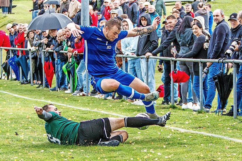 Der Mainleuser Kapit&auml;n Manuel Wollner gr&auml;tscht an der Au&szlig;enlinie vor zahlreichen Zuschauern Maximilian Wei&szlig; von der SG Oberland den Ball weg.