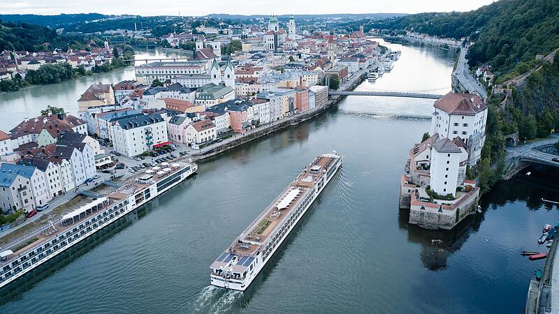 Ein Flusskreuzfahrtschiff fährt stromaufwärts an Passau vorbei