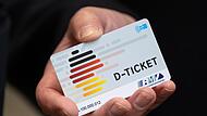 Eine Hand hält ein Deutschlandticket.