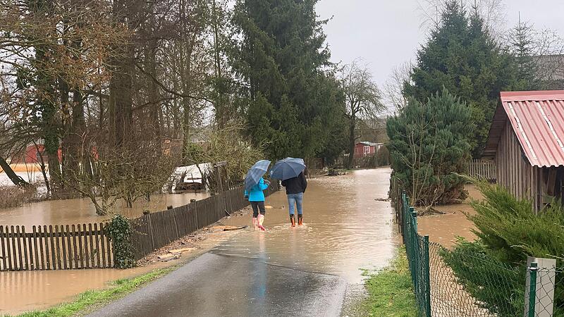 Die Wannig hat G&auml;rten und Stra&szlig;en in Gro&szlig;wenkheim &uuml;berschwemmt. Dank ihrer Gummistiefel kamen diese Spazierg&auml;nger trockenen Fu&szlig;es durch. Die ganze Nacht waren Feuerwehrleute im Einsatz, um mit Sands&auml;cken die Wohnbebauung zu sch&uuml;tzen, was auch gelu...