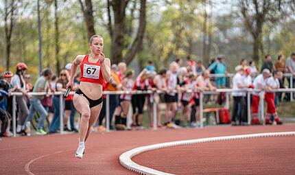 Eine Teilnehmerin des 4x400 m-Staffelwettbewerbs der Frauen l&auml;uft vor einer gro&szlig;en Zuschauerkulisse.