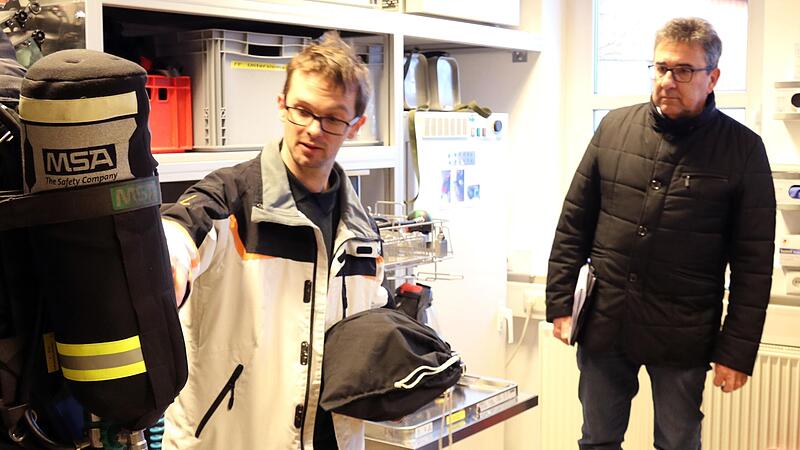 Der Atemschutzbeauftragte der Feuerwehren in Untersiemau, Dirk Engel, erklärt Bürgermeister Rolf Rosenbauer und den Bauausschussmitgliedern die Funktionsweise eines Atemschutzgerätes.