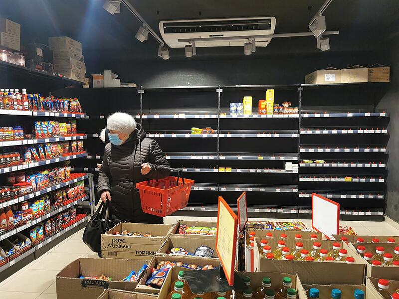 Eine Frau steht in einem Supermarkt vor teilweise leeren Regalen in der westukrainischen Stadt Lviv. Vornehmlich lagerfähige Lebensmittel waren ausverkauft.