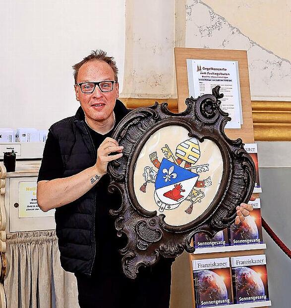 Kirchenschweizer Daniel Reitz mit dem neuen Papstwappen in der Hand.