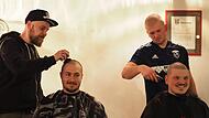 Die Fußballer Thomas Schneyer (vorne links) und Lennart Henning lassen sich von ihren Mannschaftskollegen Lukas Löhnert (hinten links) und Paul Kieser eine Glatze rasieren.