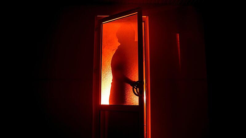 Fünf Einbrüche in einer Nacht in Motten: Polizei wendet sich an die Öffentlichkeit bedrohlich, einbrecher, türe, Silhouette einer unbekannten Schattenfigur an einer Tür durch eine geschlossene Glastür. Die Silhouette eines Menschen vor einem Fenster in der Nacht. Scary Szene Halloween Konzept der unscharfen Silhouette von Maniac.