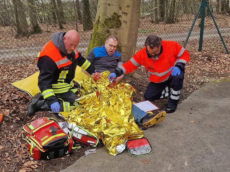 Ernstfall im Freien: Zwei Teilnehmer der Abschlusspr&uuml;fung versorgen einen Verletzten mit Rettungsdecke und Verbandsmaterial, eine von vielen realistischen &Uuml;bungsszenen beim Abschlusstag.