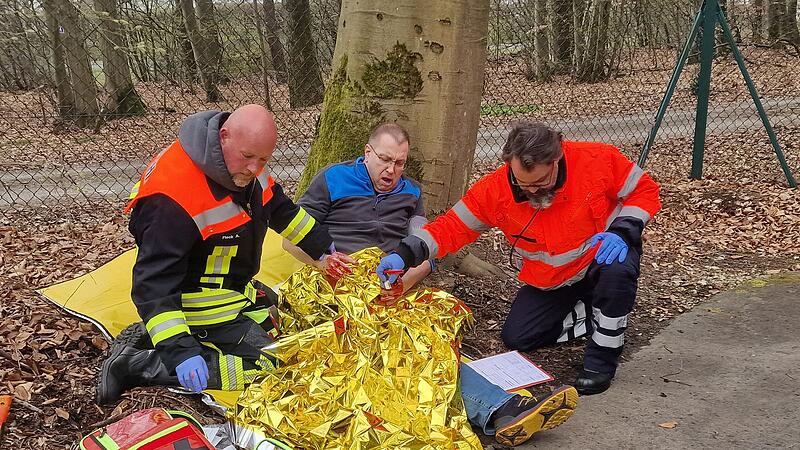 Ernstfall im Freien: Zwei Teilnehmer der Abschlusspr&uuml;fung versorgen einen Verletzten mit Rettungsdecke und Verbandsmaterial, eine von vielen realistischen &Uuml;bungsszenen beim Abschlusstag.