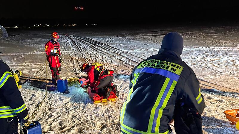 Die Retter ziehen das Opfer &uuml;ber das Eis auf dem Weiher in Dechsendorf.