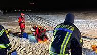 Die Retter ziehen das Opfer &uuml;ber das Eis auf dem Weiher in Dechsendorf.