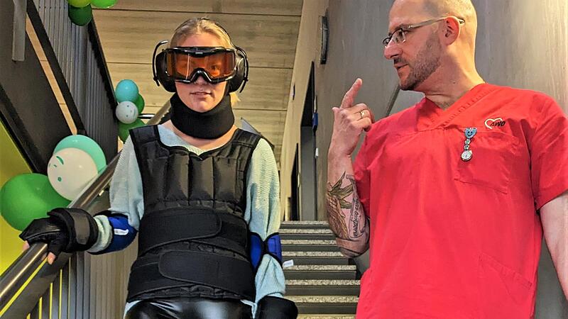 Pflegesch&uuml;ler Ren&eacute; Saft hilft Rebekka H&auml;u&szlig;ler beim Treppenabstieg im Alterssimulationsanzug.