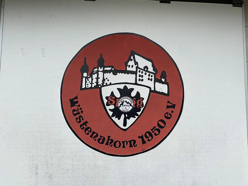 Die Fu&szlig;ballpl&auml;tze der Sportvereinigung W&uuml;stenahorn liegen mitten im Wald. Keine Chance, von dort die Veste zu sehen. Aber: Im Wappen des Vereins im Coburger Westen ist sie fester Bestandteil. Auf unserem Foto wurde sogar noch ein Aufkleber der SpVg W&uuml;stenahorn mitten aufs Wappen gekl&auml;rt.