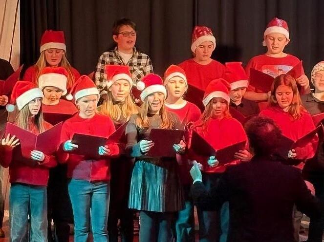 Auch der rot gekleidete Unterstufenchor mit Nikolausm&uuml;tzen unter der Leitung von Christian Moll trat auf.